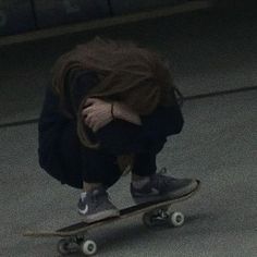 a man riding a skateboard down the middle of a street with his hands on his face