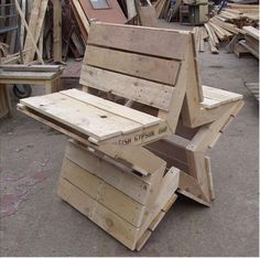 a bench made out of wooden pallets sitting on the ground next to other pieces of wood