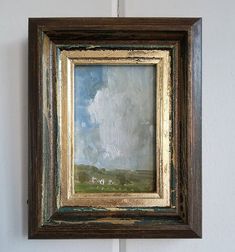 an old painting hanging on the wall in a room with white walls and wood trimmings