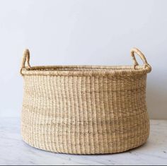 a large woven basket sitting on top of a white counter next to a planter