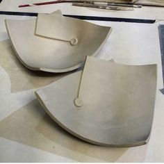 two metal bowls sitting on top of a table next to scissors and paintbrushes