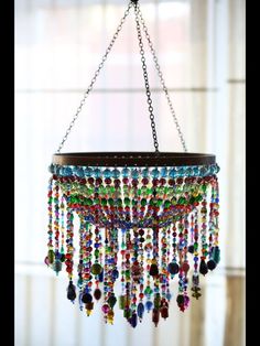 a chandelier with beads hanging from it's sides in front of a window