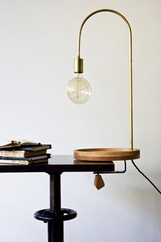 a lamp that is sitting on top of a table next to books and a plate