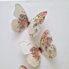 three butterflies sitting on top of each other in the middle of a white surface with floral designs