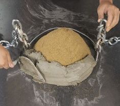 a person is holding chains around a large ball of sand that has been placed on top of it