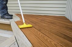 a person with a mop on their feet standing on a wooden deck next to a house
