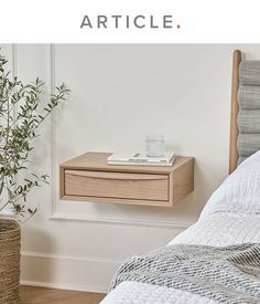 a bedroom with a bed, nightstand and potted plant on the floor next to it