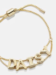 a gold bracelet with the word daisy written in large letters, on a white background