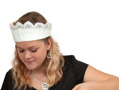 a woman wearing a tiara cutting into a piece of cake with a knife and fork