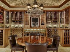 a dining room table surrounded by chairs in front of a wine rack filled with bottles