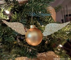 an ornament hanging from the top of a christmas tree with gold and silver decorations