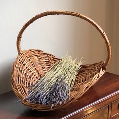 a wicker basket sitting on top of a wooden table next to a drawer with dried lavenders in it