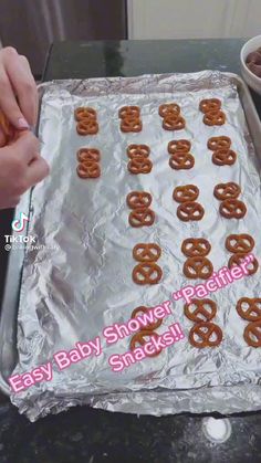 someone is decorating some pretzels on a sheet of tin foil