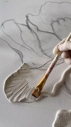 a person is painting with paintbrushes on a piece of paper