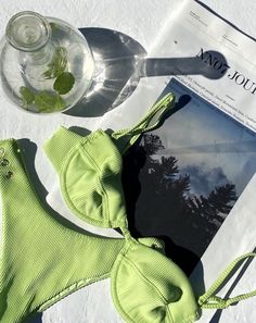 a green bikinisuit next to a wine glass and magazine