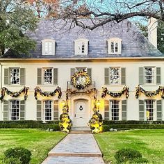 a large white house decorated for christmas with wreaths and lights