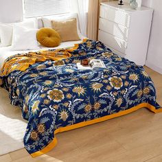 a blue and yellow bedspread on a bed in a room with white walls