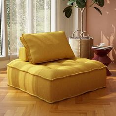 a yellow chair sitting on top of a hard wood floor next to a potted plant