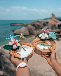 two people holding coconuts with flowers on them