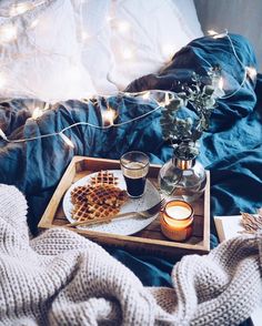 a tray with waffles, coffee and candles on it next to a blanket