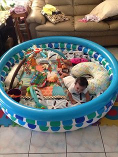 a young child laying in an inflatable pool with toys all over it's surface