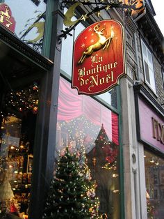 a christmas tree is in front of a store window with lights and decorations on it