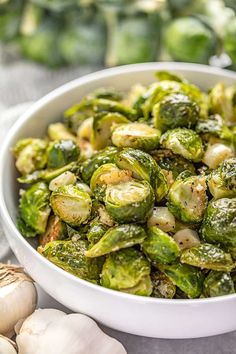 a white bowl filled with brussel sprouts and garlic