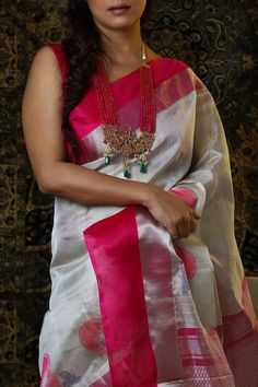 The electrifying fuchsia pink is balanced by a sedate white to create a combination which is bold yet elegant. The peacock motifs enhance the beauty of the saree by adding an element of interest. This saree is as unique as your smile!   Details Fabric: Tissue and Zari fine blend handloom Color and Design: White-fuchsia Fabric