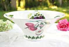 a bowl sitting on top of a table with flowers in the backgroung