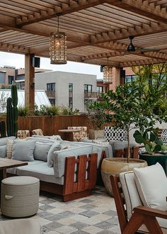 an outdoor living area with couches, tables and potted plants