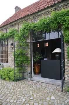 an old brick building with ivy growing on it's sides and the door open