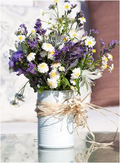 a bouquet of wildflowers and daisies in a tin can