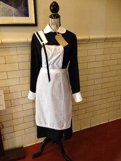 a white and black apron on a mannequin in front of a brick wall