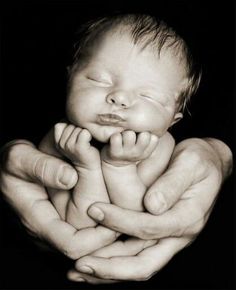 a black and white photo of a baby in the hands of someone's hand