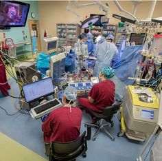 two doctors in scrubs are working on computers and medical equipment inside an operating room