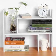 a white book shelf with books and a clock on it next to a coffee cup
