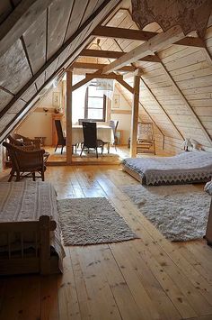 an attic bedroom with two beds and desk in the corner on the far wall is a loft
