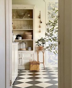 a kitchen with black and white checkered flooring next to an open pantry door