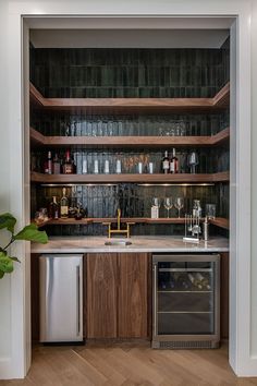 a kitchen with an oven, dishwasher and wine glasses on the shelves above it