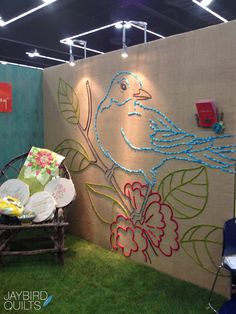 a wall with a bird painted on it next to a lawn chair and table in the grass