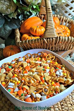 a white bowl filled with halloween treats next to a wicker basket full of pumpkins