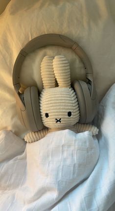 a stuffed bunny with headphones on laying in bed