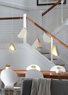 some chairs and tables in a room with lights on the ceiling above them is a stair case