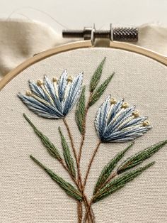a close up of a embroidery on a piece of cloth with some flowers in it