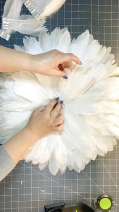 two hands are working on some white feathers