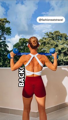 a woman in red shorts holding two blue dumbbells over her head with the words back on it