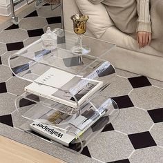a glass coffee table with magazines on it and a magazine rack in front of it