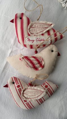 three red and white bird ornaments hanging from strings on a table cloth covered tablecloth