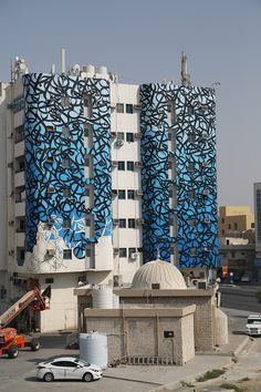 a large building with blue and white designs on it's side next to a parking lot