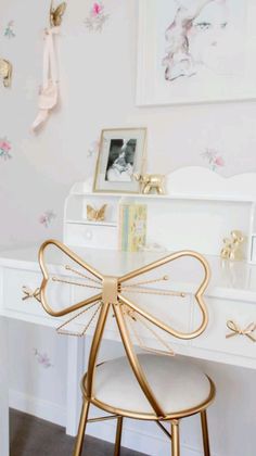 a white desk with a gold bow on it's top and some pictures above it